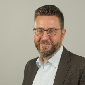 Prof. Dr.-Ing. Marc Stautner smiles as a professor at the University of Applied Sciences Ruhr-West, following a successful career at ModuleWorks and his ongoing role as Research Director, bridging academia and industry.